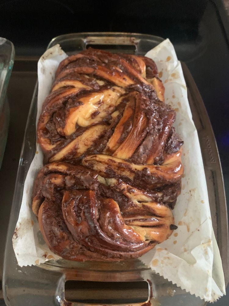 Chocolate tahini babka in parchment lined loaf pan, fresh out of the oven. 