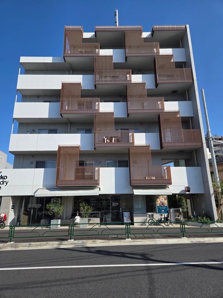 A six-story white apartment building with protruding brown wooden porch extensions that look like the Tetris L shape.