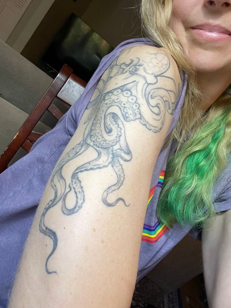Snake contorting herself to show off an octopus tattoo on her upper arm.