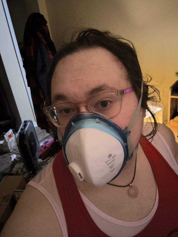 brown-haired caucasian woman, age 34, Julie, wearing an EnvoMask Pro N99 respirator. It fits with her big glasses. She has cute hooded eyes. 