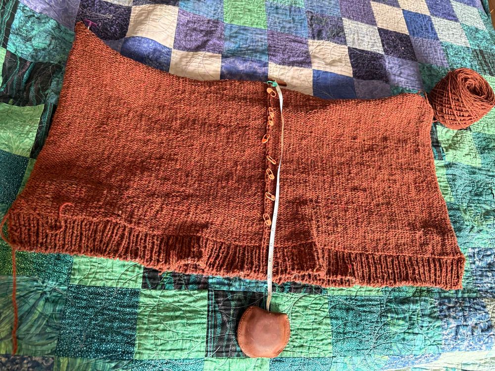 The bottom half of a sweater is laid out on a quilt
