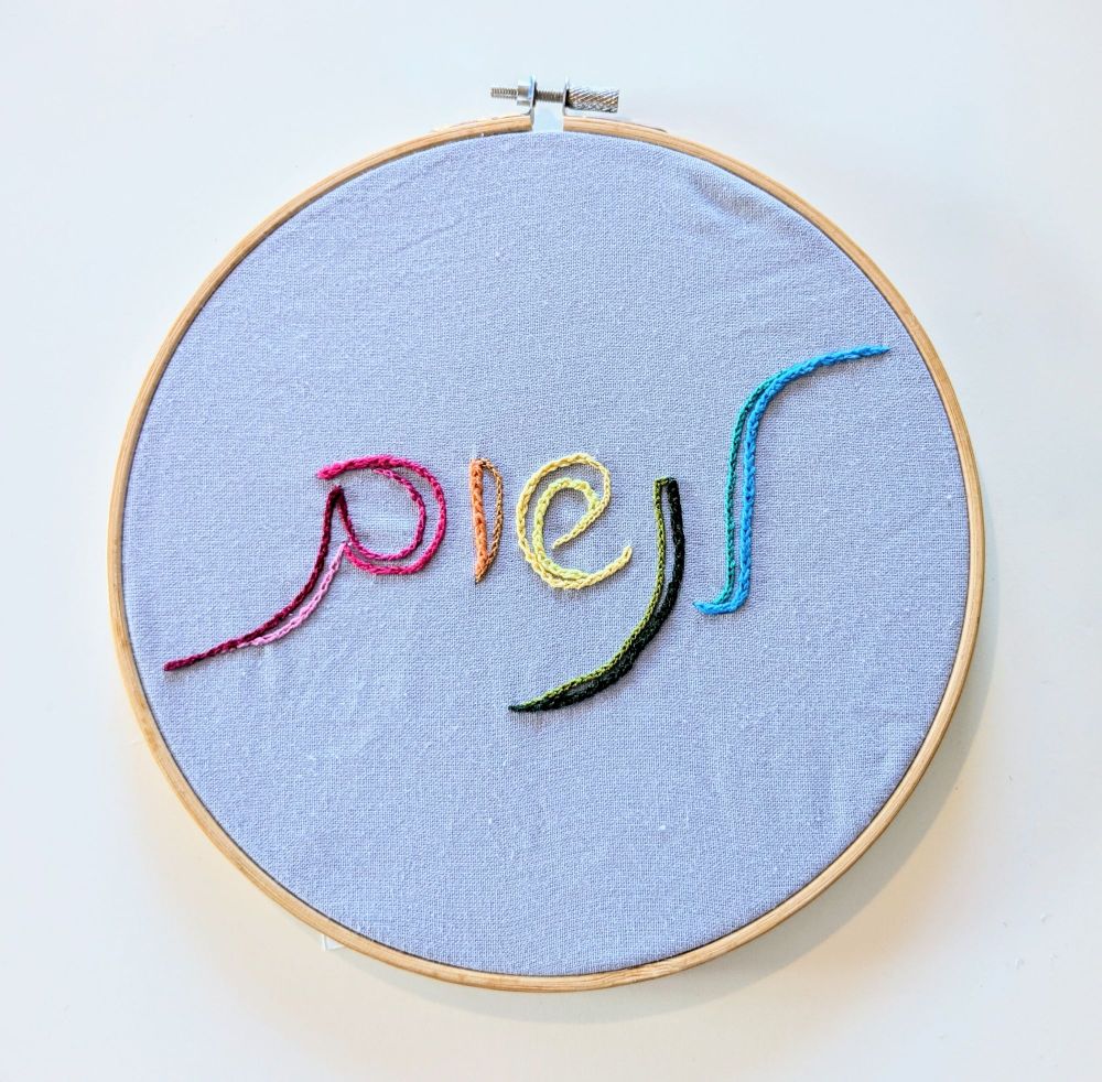 חישוק רקמה שכתוב בפנים "לנשום" בצבעי הקשת