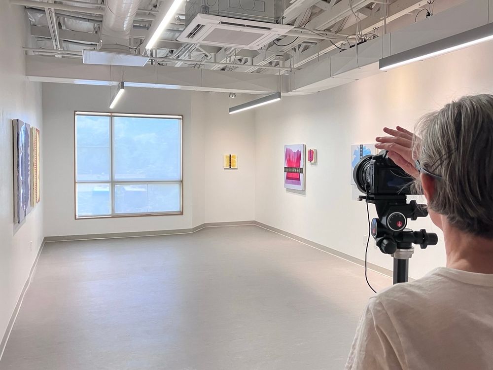 Artist Amy Vensel taking a photograph of the installation of her abstract paintings at 1415 Gallery in Albuquerque, New Mexico.