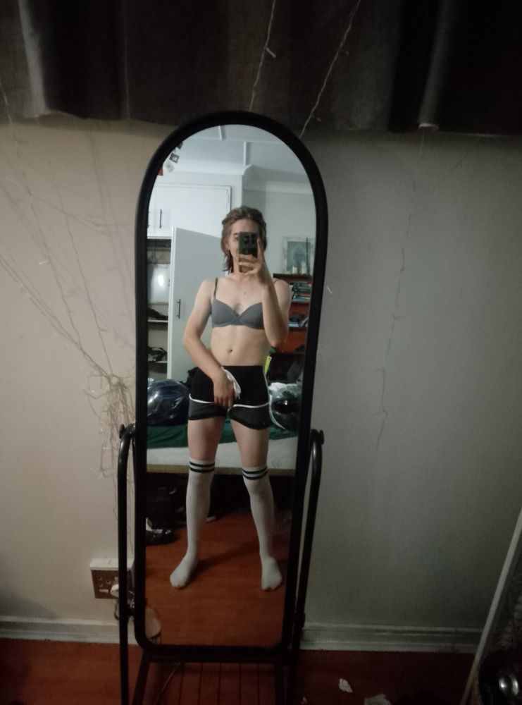 Me gripping my crotch in a bra, femboy shorts and thigh highs