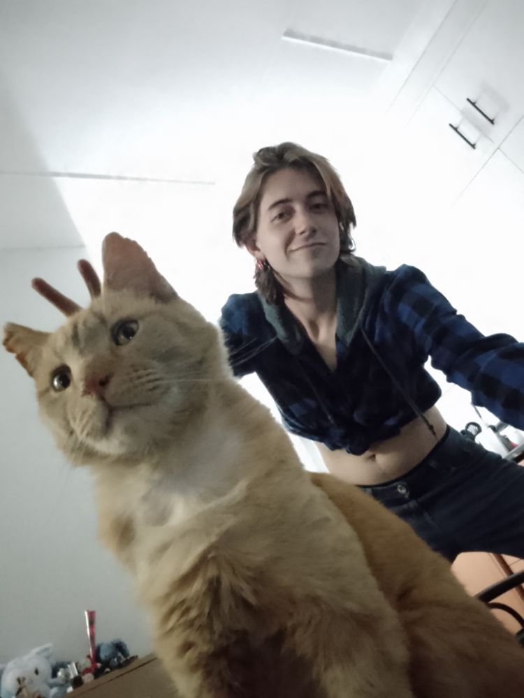 Me posing bunny ears With our cat Tom, wearing a blue plead hoodie and blue jeans