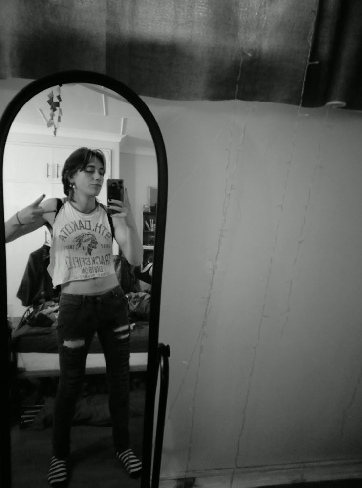 Mirror selfie of me in a white crop top vest and black ripped skinny jeans