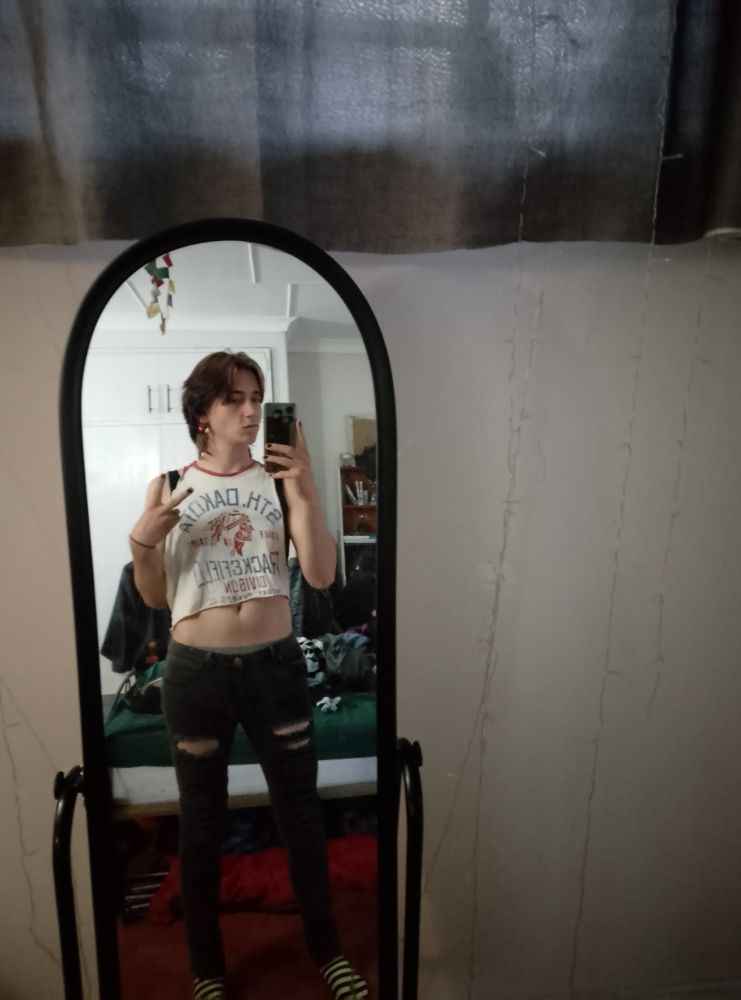 Mirror selfie of me in a white crop top vest and black ripped skinny jeans