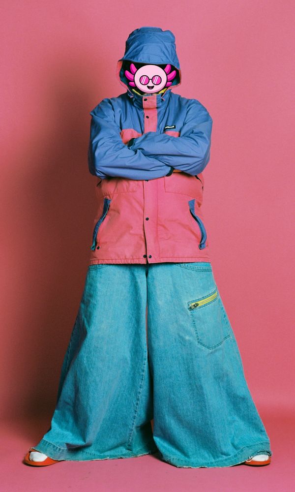 Ivy the cartoon axolotl wears a color block jacket and absolutly enormous JNCOs, standing in front of a pink backdrop.