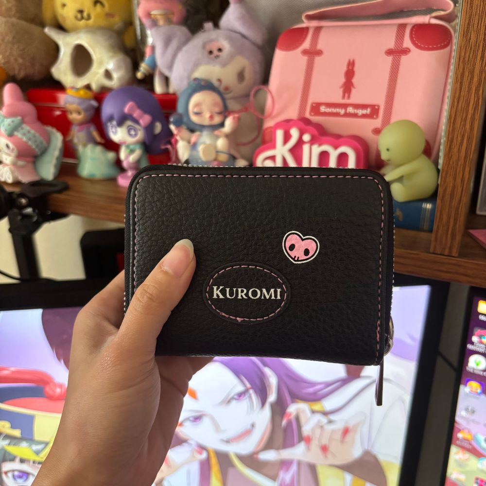 Back of Kim’s wallet. It has kuromi on the lower part of the wallet with pink stitching around and a small pink heart. 
