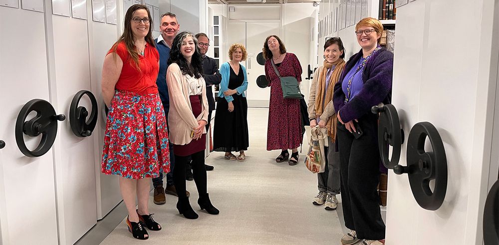 A group of people standing next to movable shelving units.
