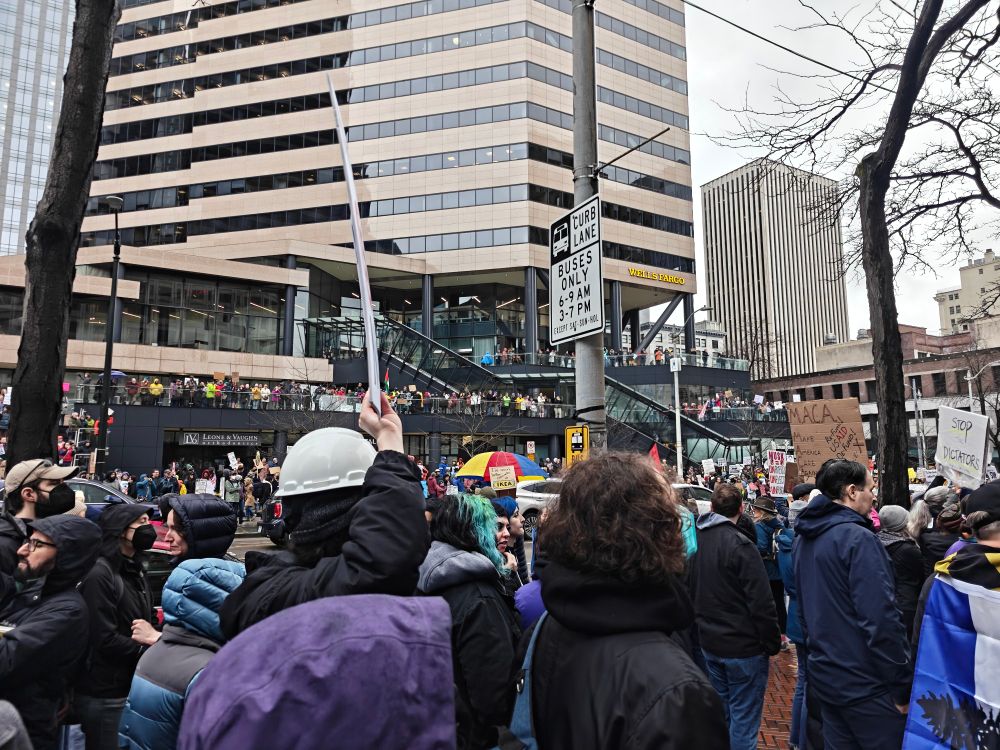 Protestors at the Federal building in downtown Seattle, including a view of protestors lined up across the street on the sidewalk and multiple balconies