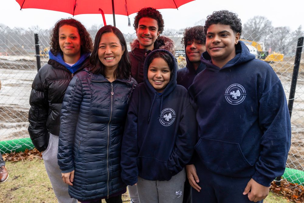 Mayor Wu smiles and stands under an umbrella with BPS students.