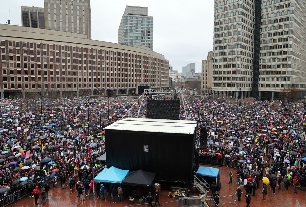 Thousands of people standing together around a stage on City Hall Plaza.