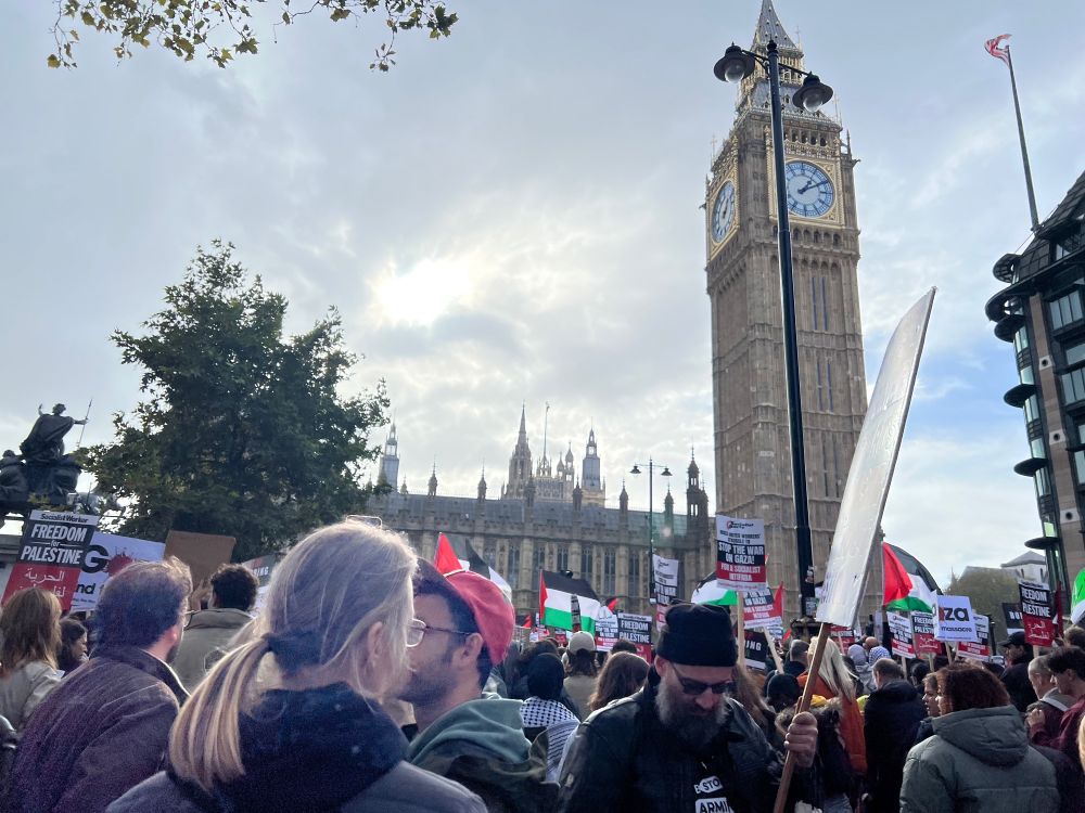 Photo of the rally for Palestine in London on October 28, with a big crowd and many Palestinian flags. Big Ben and Westminster can be seen in the background.