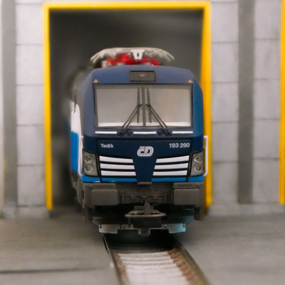 A blue and white model class br 193 vectron locomotive in CD livery standing infront of a maintenance hall