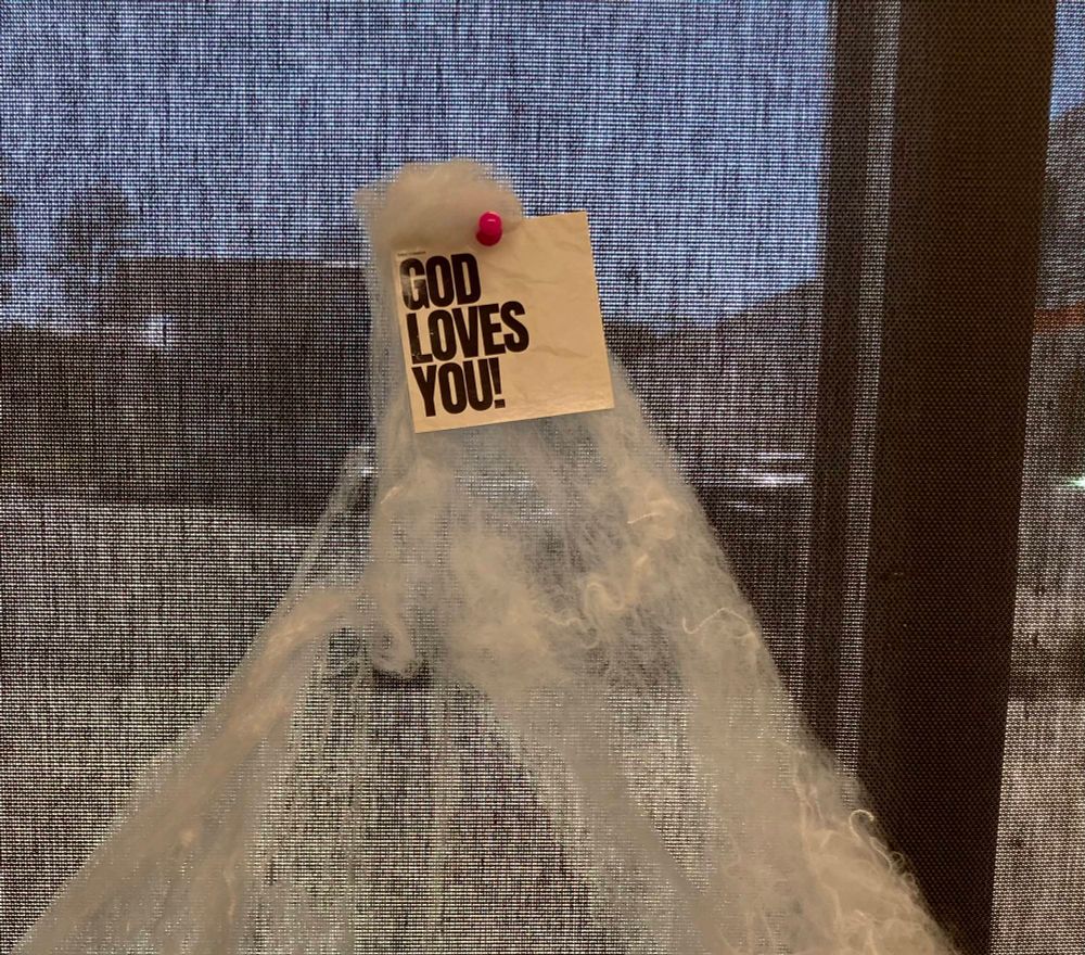 Fake halloween spiderweb with an attached sticker that says “God Loves You!”