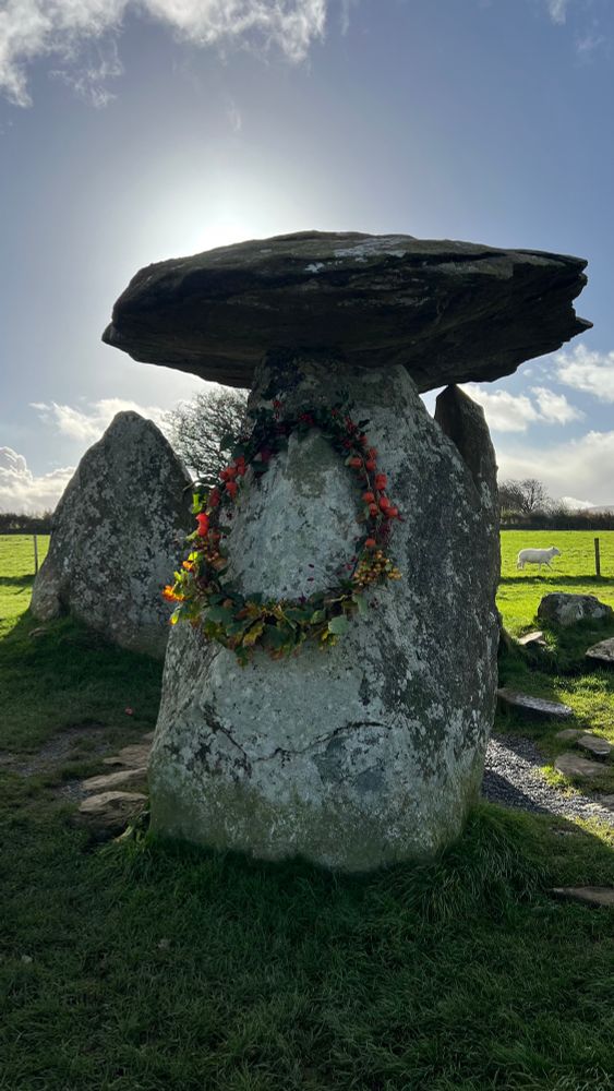 Photograph of Pentre Ifan, a Neolithic dolmen. It is taken on 1st November. Someone has lain a wreath hanging from the northern stone, presumably to mark Samhain.
