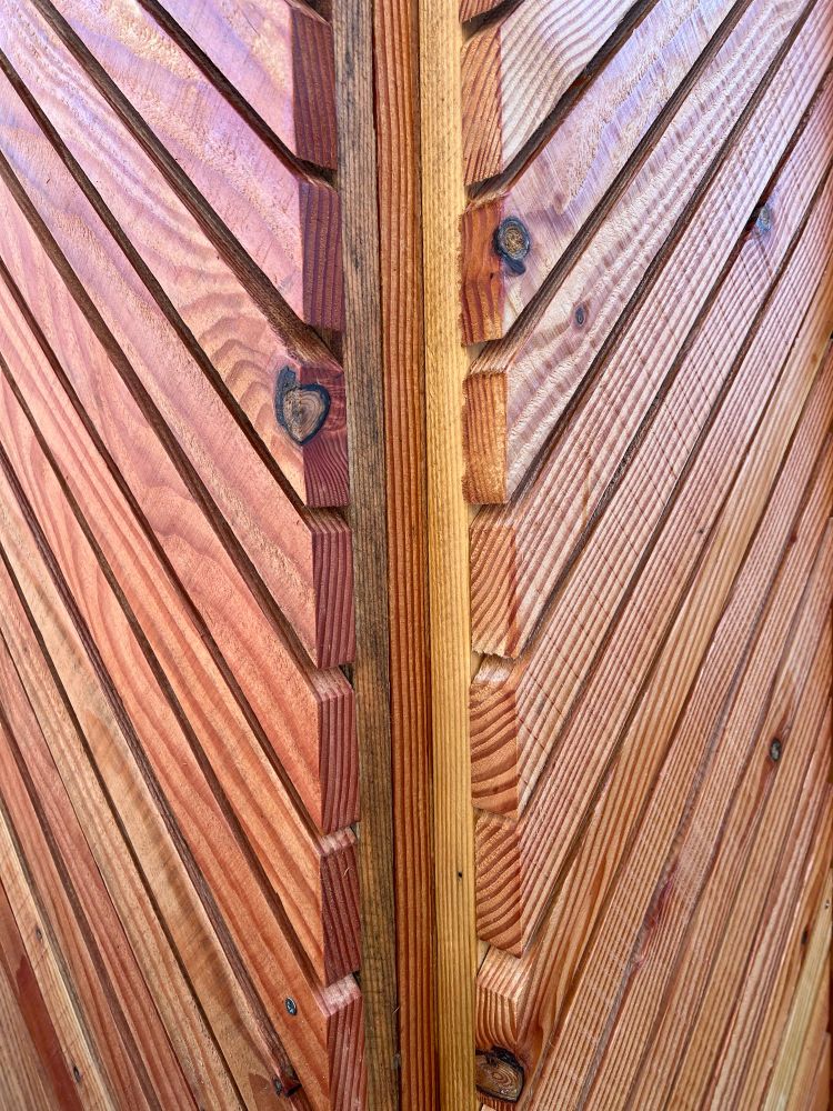 Photograph of two cladding panels installed on the corner of a structure, forming a chevron pattern