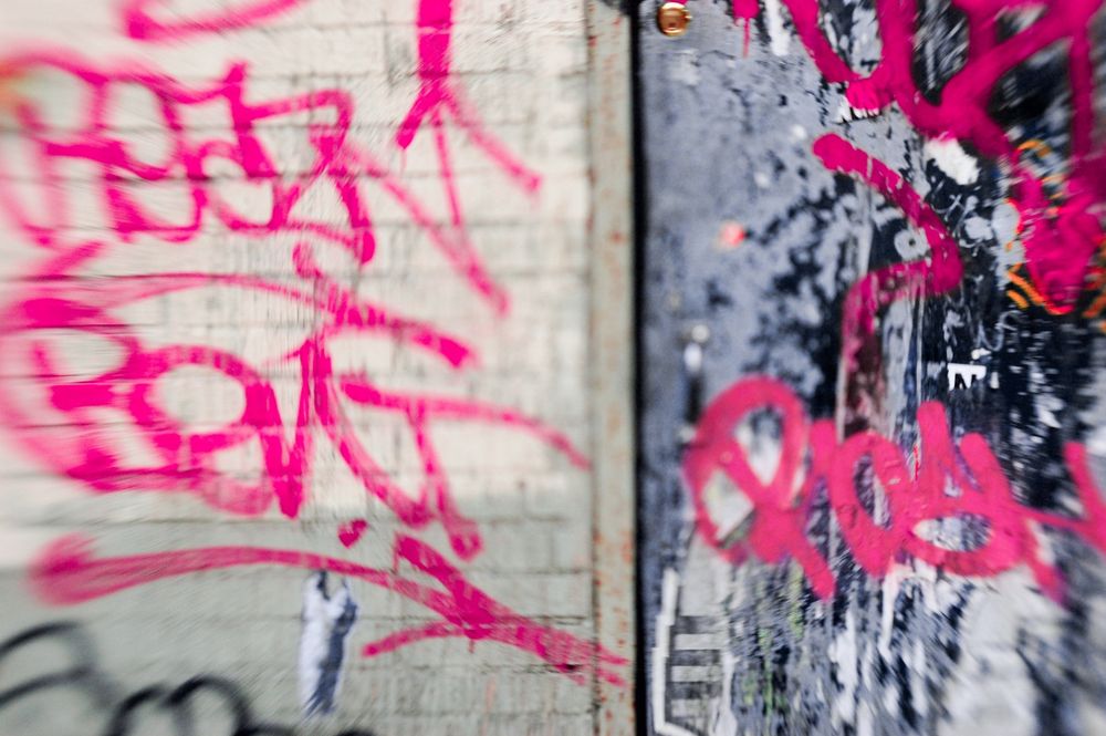 Hot pink graffiti on a wall that is half grey and half beige