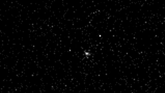 A slightly blurry starfield, with a brighter white splotch in the very middle of the image. The brighter splotch is comet 3I/ATLAS.