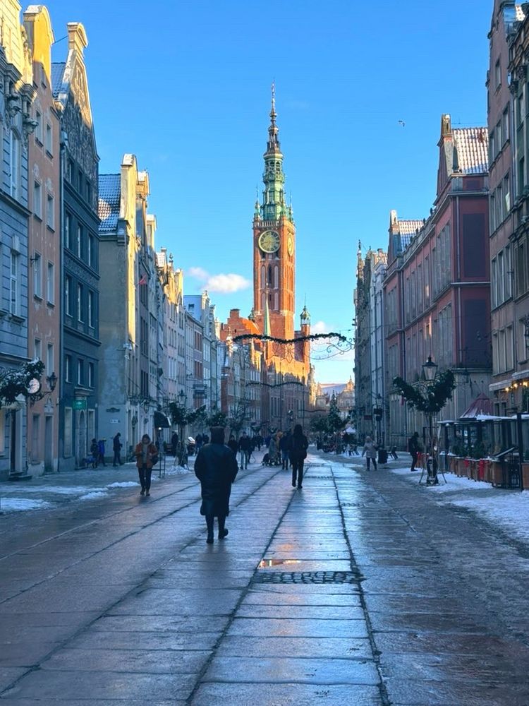 Długa, or the Long Market, in Gdańsk, Poland. The town hall clock tower is bathed in golden hour sunlight in the background.