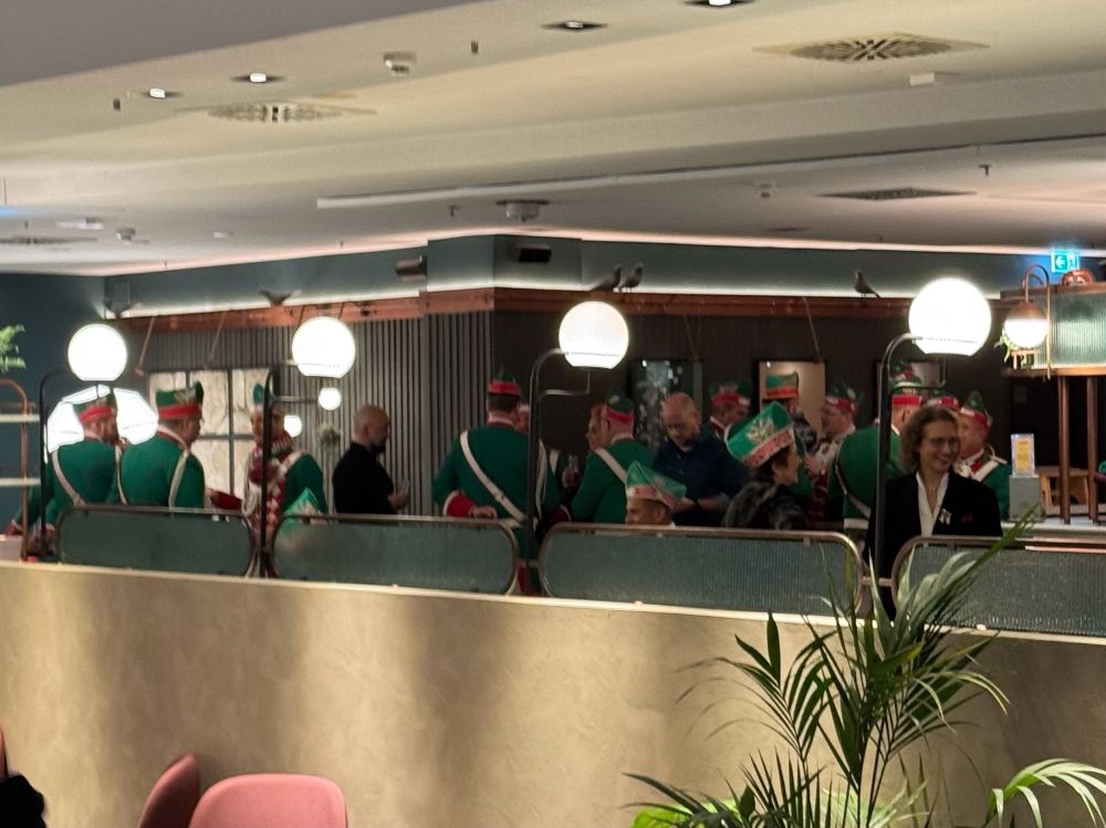 More men dressed up in bright green uniforms and green hats in a hotel lobby 