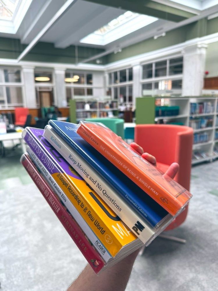 A colourful pile of books being held up in a library