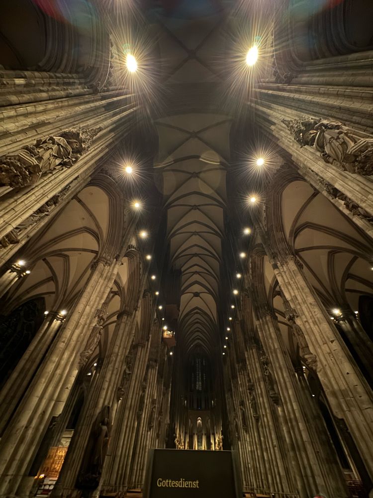 Interior ceiling shot of Cologne Cathedral. Lots of columns and lights 
