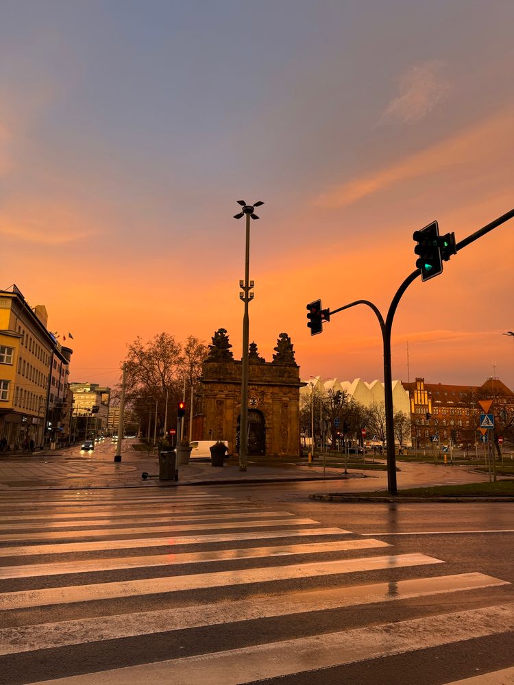 A fiery peach coloured sky above a royal gate in Szczecin Poland 