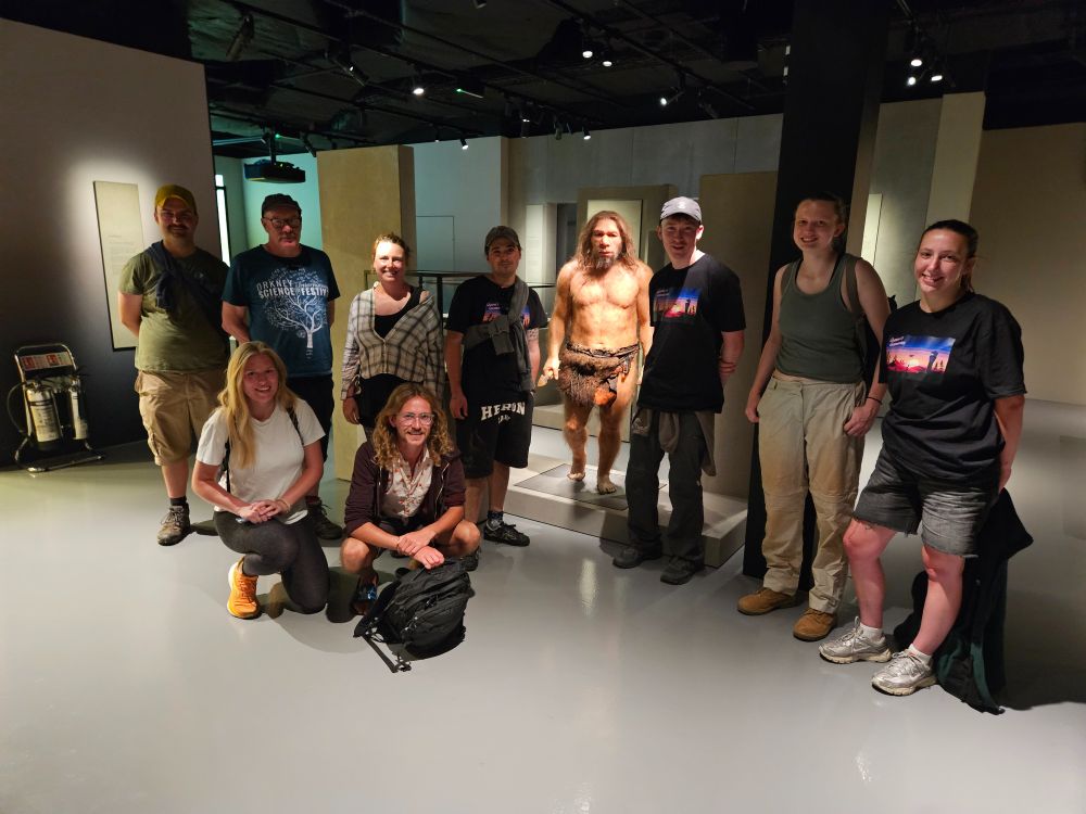 People standing with a model of a neanderthal person