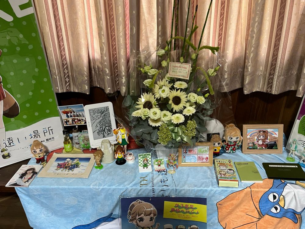 真ん中には様々な歴代のよりもいグッズや自作グッズが所狭しと並べられており、真ん中には日向の誕生日を祝う豪華なお花が！🏵️
絵も素敵だし、フィギュアやスタンド、ぬいも可愛くて日向好きにはたまらない空間になっていて良いですねぇ〜🥳

何気に右下にあるよりもいオフ会の名札コレクションってのもちょっと中身見てみたかった気がする(笑)