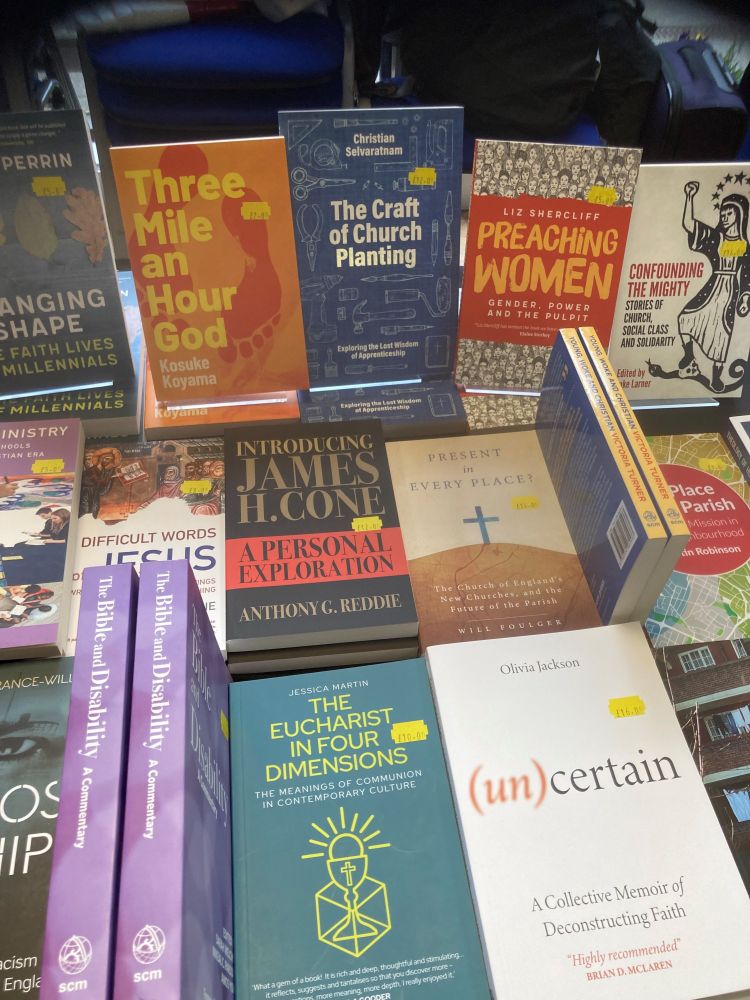 A bookstall filled with SCM Press books, including Three Mile an Hour God, The Craft of Church Planting, Preaching Women, Confounding the Mighty, The Eucharist in Four Dimensions, (Un)Certain, The Bible and Disability, Present in Every Place, Introducing James H Cone