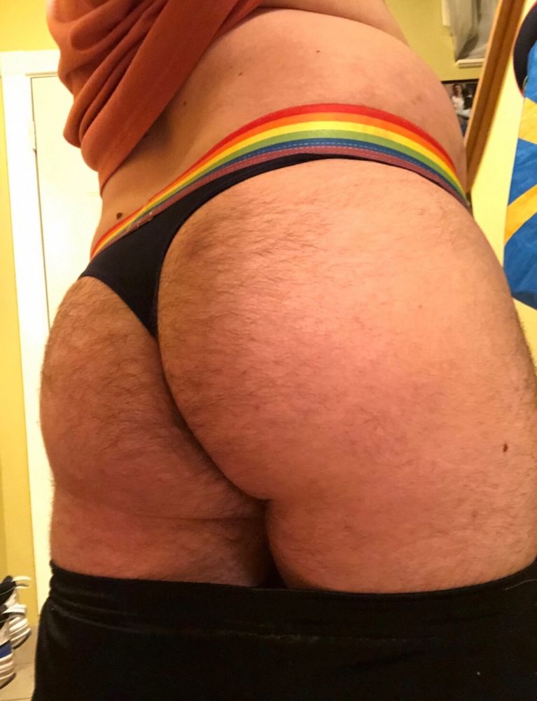Thicc, hairy puppygirl bum wearing a navy blue thong with a rainbow waistband and pants pulled down just below my butt to expose it