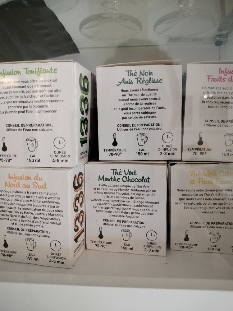 Photo moche de six boites de thès et infusions 1336, dans une armoire vitrée. 