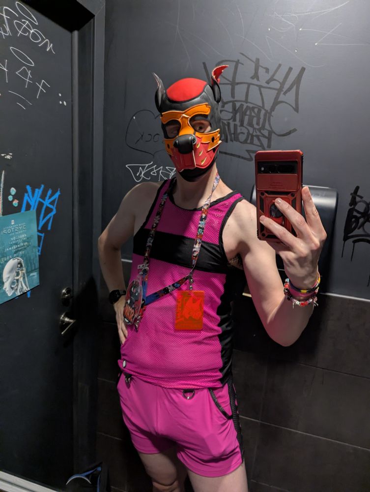 Scani in pink shorts, a mesh top, and red and orange pup hood.