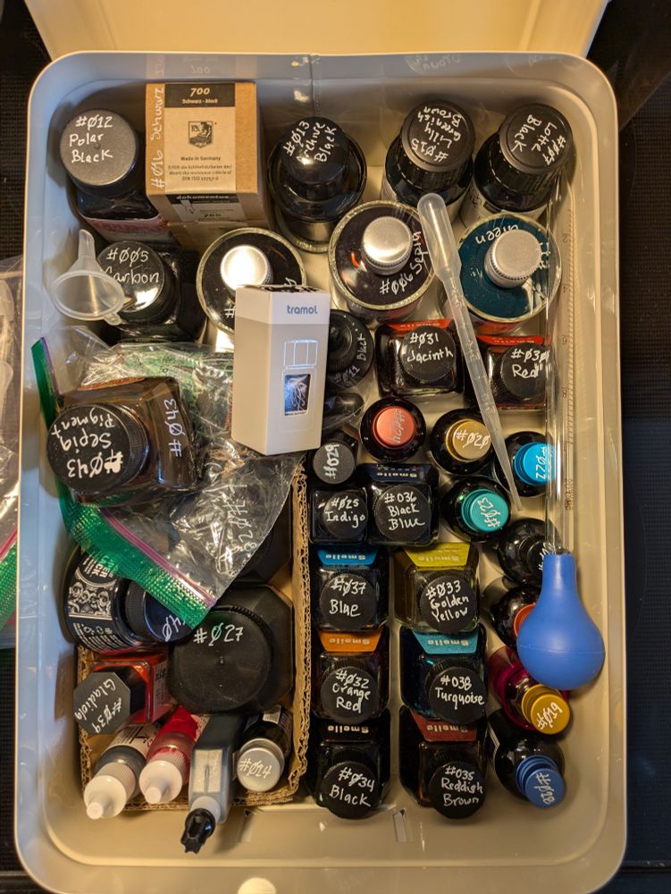 A metal container filled to capacity with many different liquid inks for drawing and writing