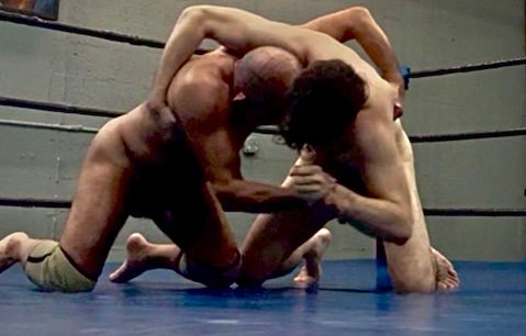 Older muscled wrestler locked up with younger lean wrestler 