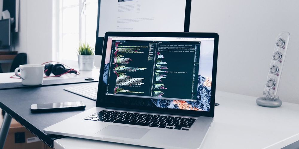 Photo of a laptop on a desk with screen of code/network (photo_by_christopher_gower_on_unsplash_system-admin)