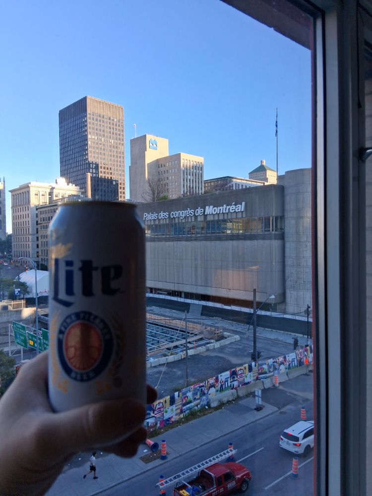 Cityscape of Montreal in the background. Hoisted can of Miller Lite in the foreground 