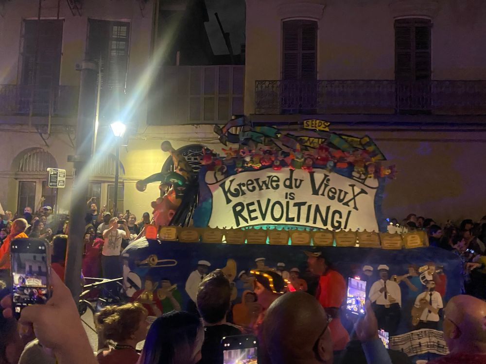 A crowd of parade watchers in front of a parade float