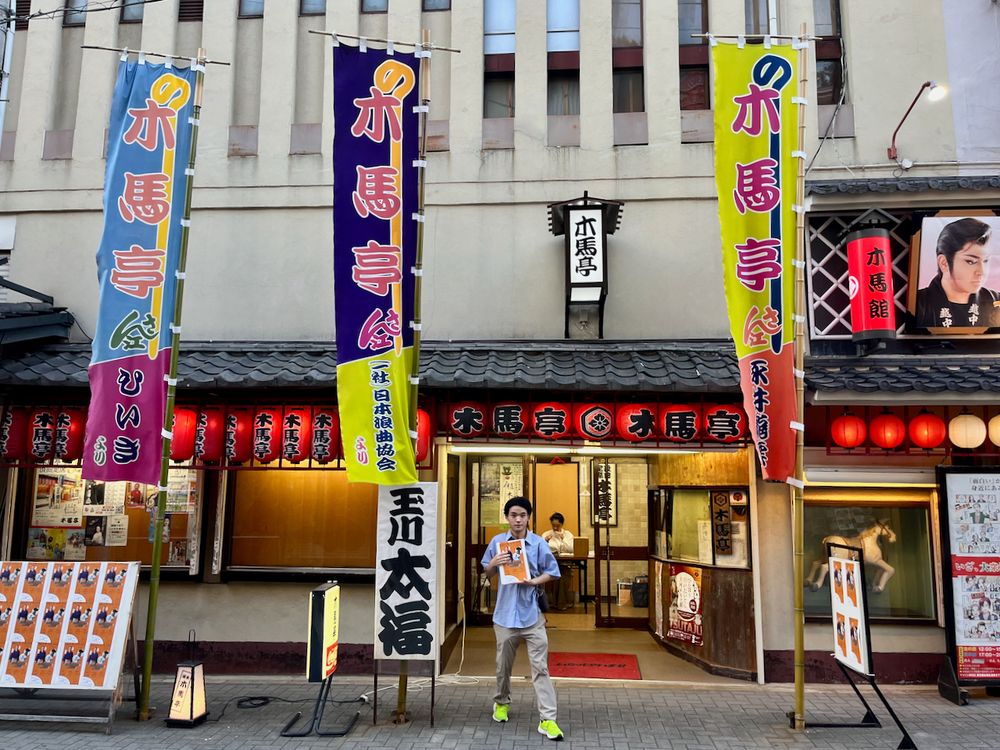 Young man standing in front of traditional Japanese theater Mokubatei.