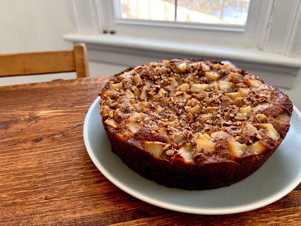 round cake covered in pear chunks on a table in front of a window 