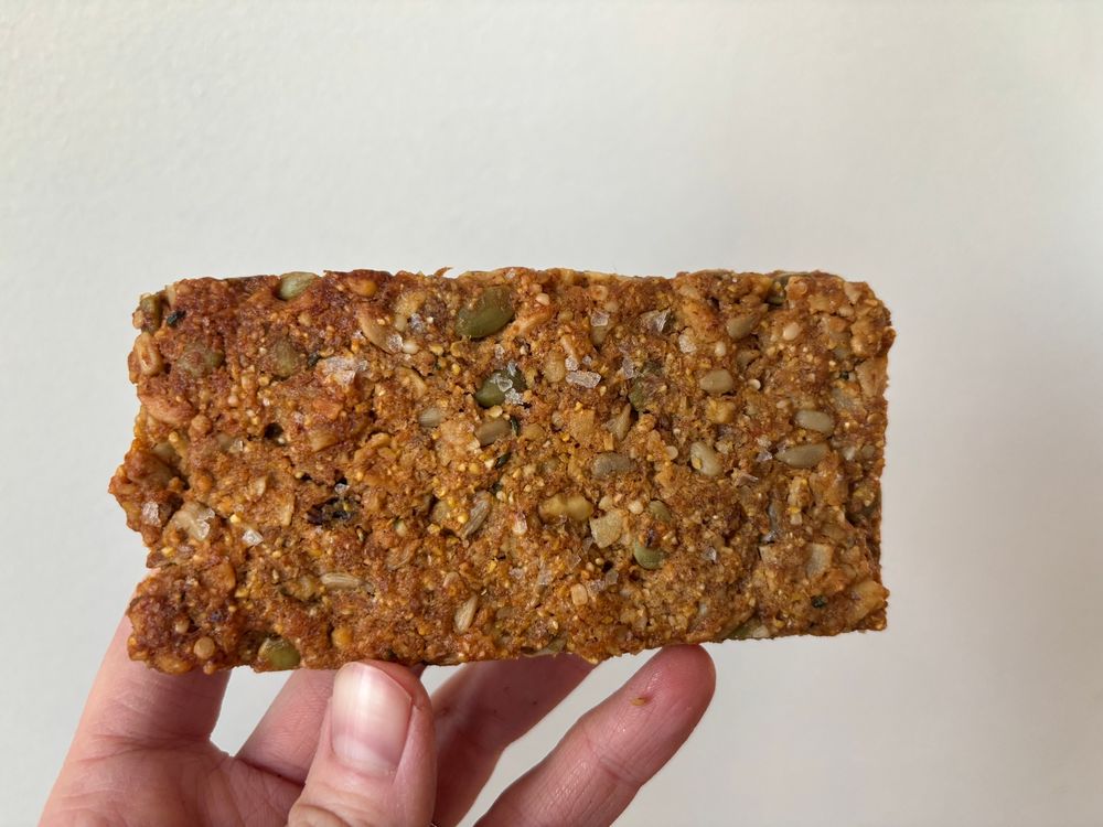 a golden brown granola bread sprinkled with salt held by a hand