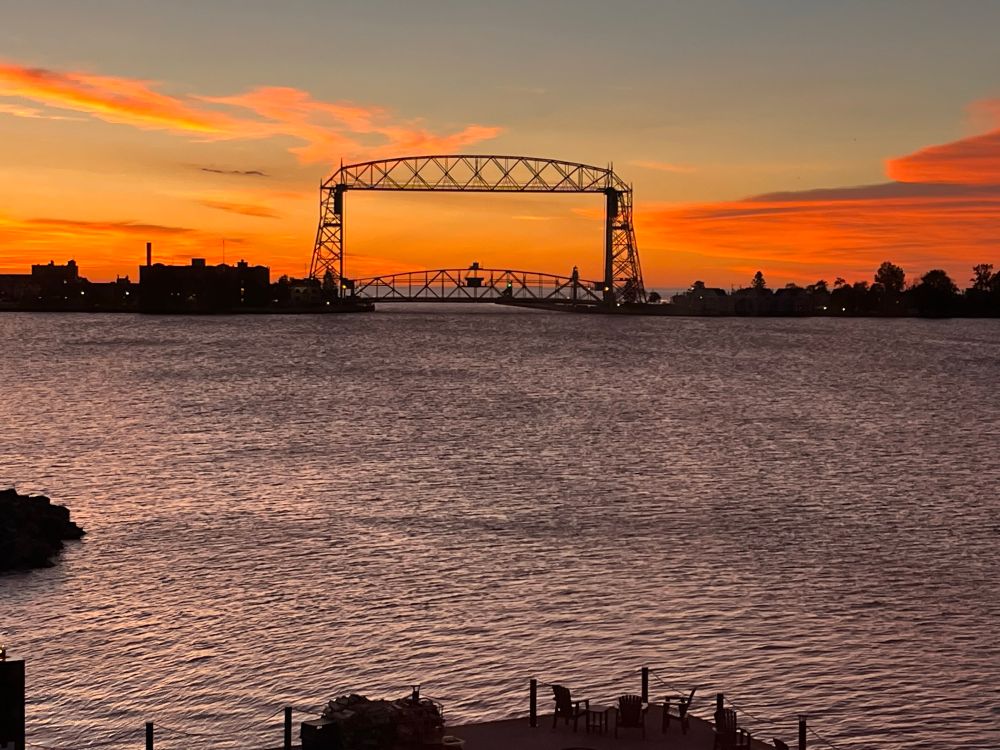 Aerial Lift Bridge Duluth MN at sunrise -bright red orange horizon with blue sky above. City Bayside Harbor of L. Superior in forefront