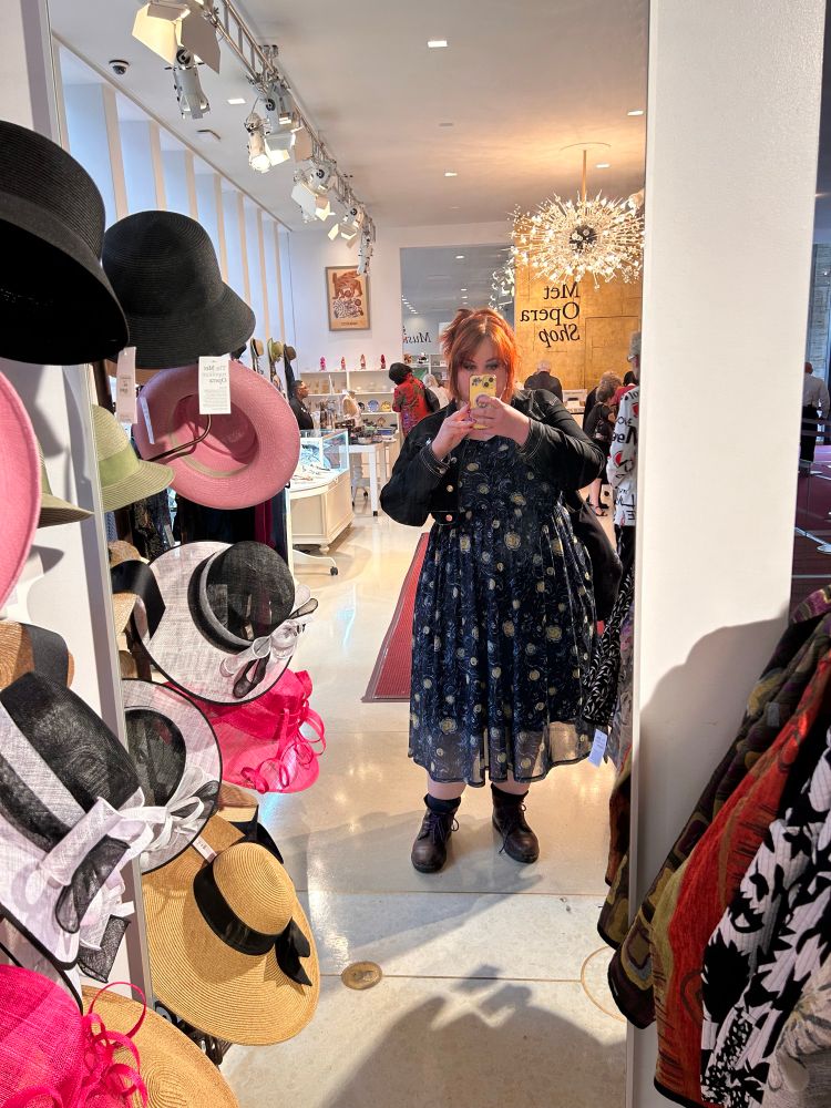 A mirror selfie of a plus size woman with red hair wearing a dress patterned with van Gogh’s Starry Night