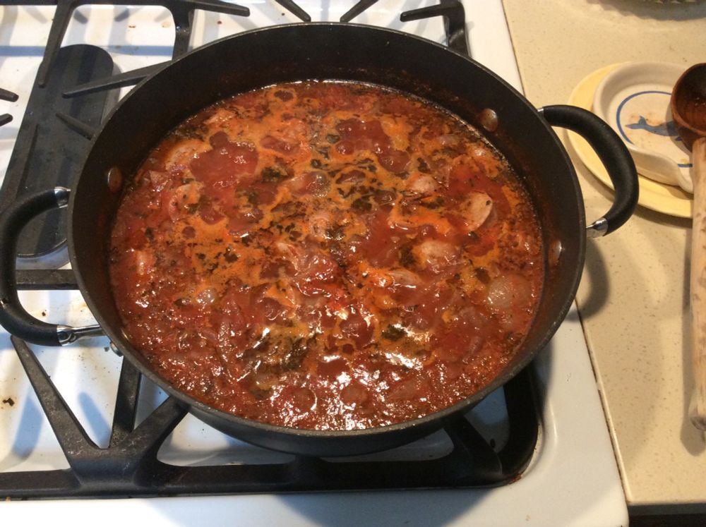 a tomato based sauce bubbling away on a white stove top
