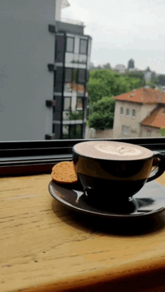 a cup of coffee sits on a saucer next to a cookie on a table