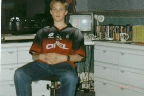 Picture of a surprisingly skinny teenage me in an extremely 90s bedroom, wearing a Milan training top and sat in front of a desk. SWOS is on the TV display and you can see my Mega Drive collection and Fighting Fantasy books behind me 