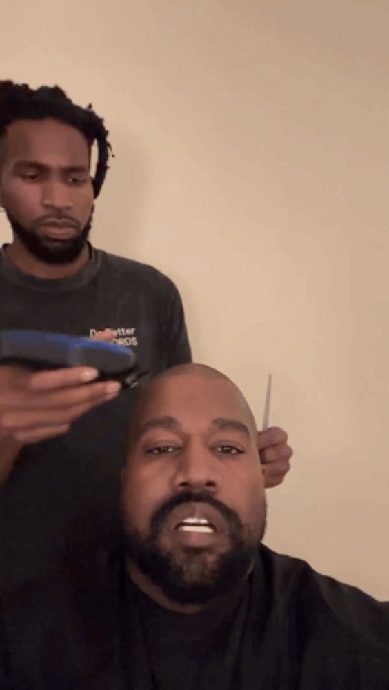 a man with a beard is getting his hair cut by another man