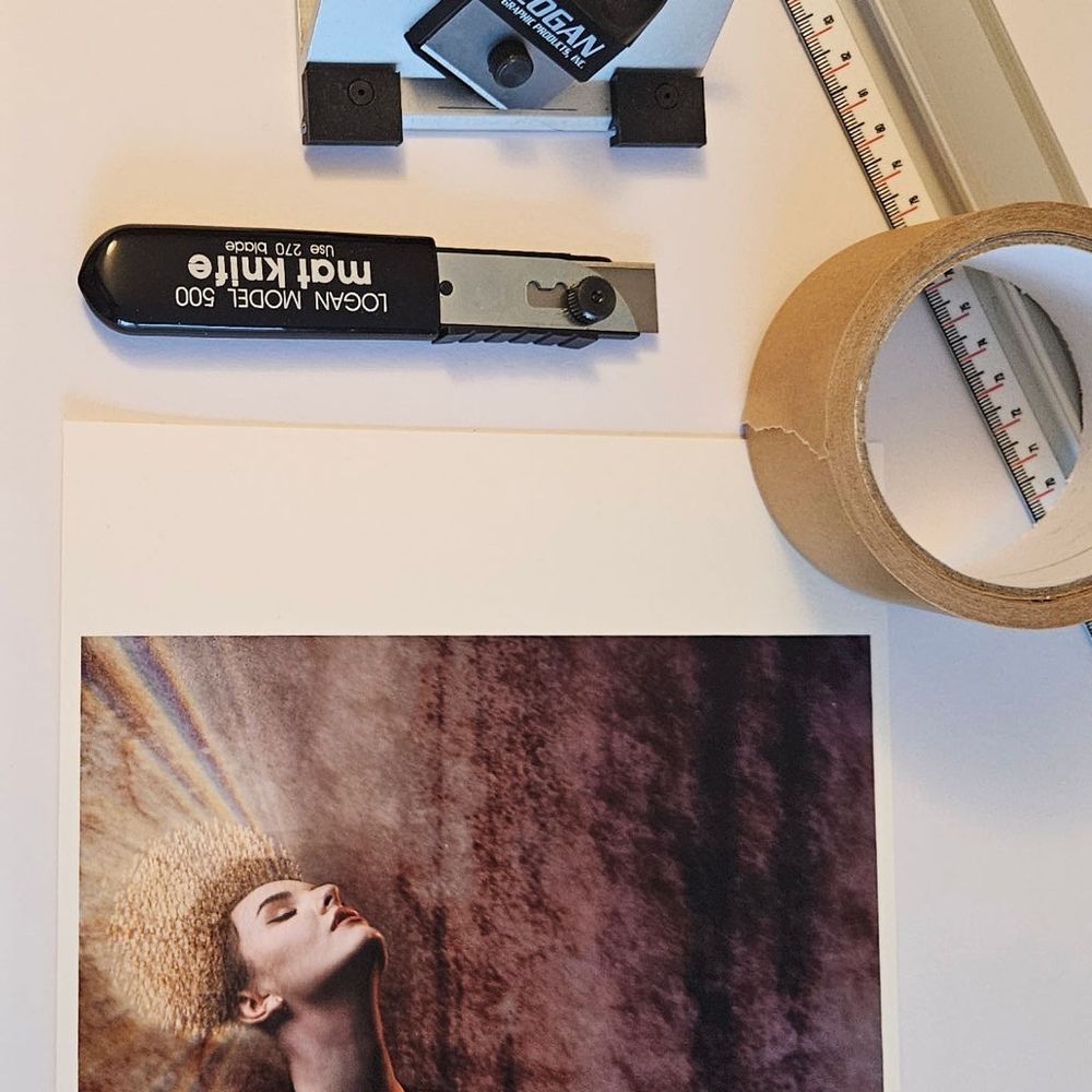 Part of a picture with a face and halo-like lights, also a ruler, tape and mount cutters.